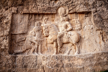 Relief depicting the triumph of Persian King Shapur I over the Roman emperors Valerian and Philip the Arab at Naqsh-e Rostam necropolis in Iran - 423654828