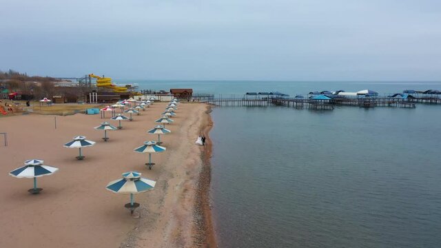 Newlyweds are walking along the shore. Bird's-eye view.