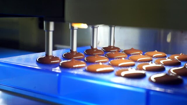 liquid chocolate mass is poured from the machine. close-up