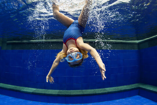 Funny Portrait Of Child Learning Swimming, Dive In Blue Pool With Fun - Jumping Deep Down Underwater With Splashes. Healthy Family Lifestyle, Kids Water Sports Activity, Swimming Lesson With Parents.