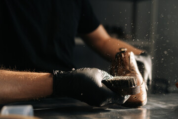 Close-up of unrecognizable man in black latex gloves cleaning shoe brush, brushing dust and dirt...