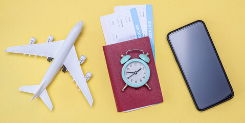 Miniature of an airplane, airline tickets with a passport and an a watch on a yellow background. Time for travel