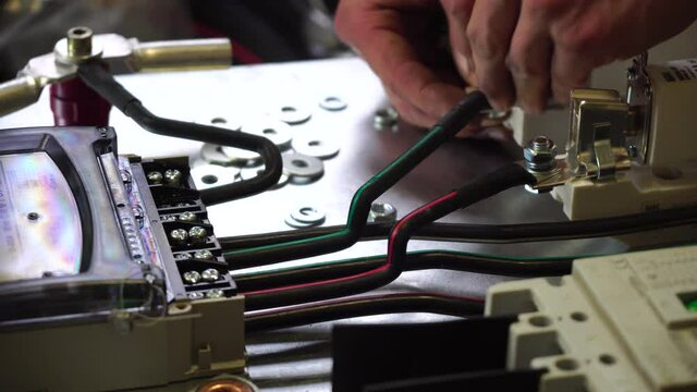 Close-up view of Electrician installing wires, cables into a electricity power shield, fuse box, an industrial electric panel with lots of colorful cables and wires. Power industry concept.