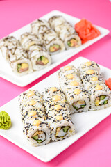 Sushi large set served on a white plate over pink background. Traditional Asian Japanese cuisine concept.