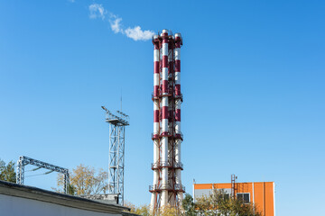 View of the thermal power plant. Clouds of white steam rise into the sky from the chimney.