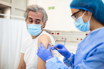 Fototapeta premium An elderly man receiving the injection of the coronavirus vaccine by a doctor to receive the antibodies, immunize the population. side effects, risk people, antibodies, new normal, covid-19.
