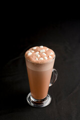 Hot chocolate with marshmallows isolated on black background. Glass of cocoa over black.