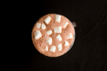 Hot chocolate with marshmallows isolated on black background. Glass of cocoa over black.