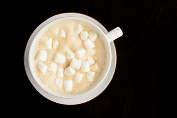 Fototapeta na wymiar Cup of latte coffee with marshmellows over black background. Coffeee time, isolated on black.