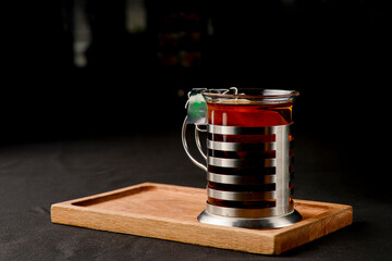 Cup of tea over black background. Tea time, tall glass with black tea.