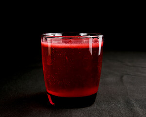 Refreshing fruit punch beverage in glass over black background. Isolated on black.