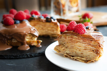 Pancakes with dessert filling and berries on a dark background.