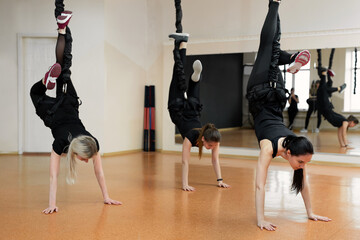 Close-up group of girls hanging on bungee rubber bands in the gym. Girls perform a difficult exercise with bungee gum