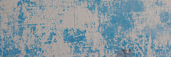 Peeling paint on the wall. Panorama of a concrete wall with old cracked flaking paint. Weathered rough painted surface with patterns of cracks and peeling. Wide panoramic texture for design background