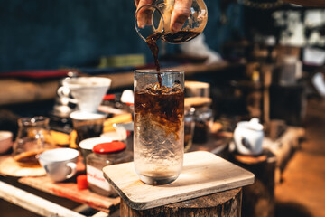 Making Iced coffee,Hands are pouring coffee into a glass of cold water.