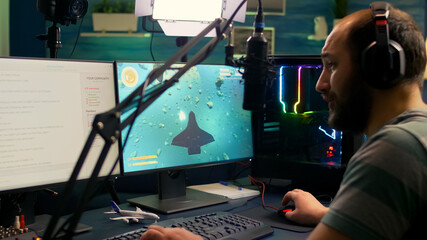 Pro streamer man playing space shooter video games during online competition using professional setup with chat open. Gamer streaming video games on professional powerful computer