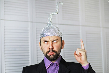 Bearded funny man in a cap of aluminum foil. Concept art phobias.Conspiracy theory. Conspiracy....