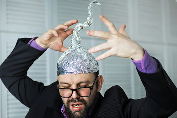Bearded funny man in a cap of aluminum foil. Concept art phobias.Conspiracy theory. Conspiracy....