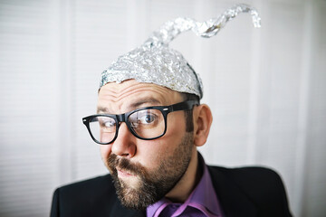 Bearded funny man in a cap of aluminum foil. Concept art phobias.Conspiracy theory. Conspiracy....