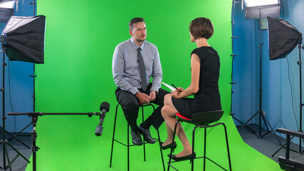 Female presenter interviewing man with pixelated and hidden face in tv studio
