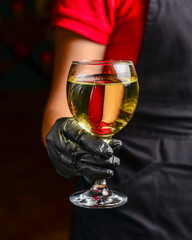 Professional waiter in uniform is serving wine in a glass. Champagne serve for party or celebration in restaurant.
