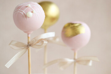 The pastry chef decorates cake pops with satin ribbons.Various cake pops decorated with white and dark chocolate on a brown background. High quality photo.