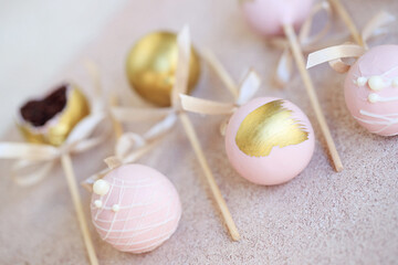 The pastry chef decorates cake pops with satin ribbons.Various cake pops decorated with white and dark chocolate on a brown background. High quality photo.