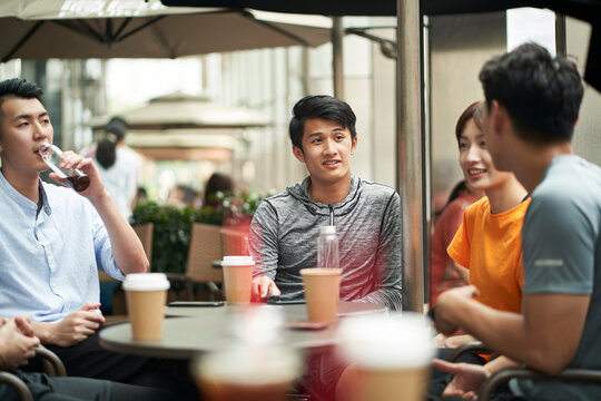 group of young asian adults relaxing at outdoor coffee shop