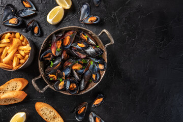 Mussels with lemon, toasts, and French fries, an overhead shot