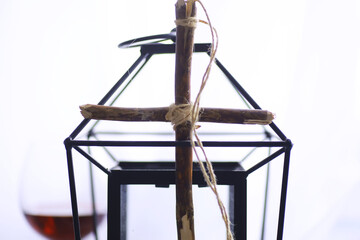 Fototapeta na wymiar Religious concept. Handmade wooden cross on a white background. Wine glass lamp with candles.