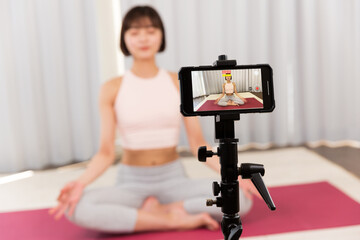 スマートフォンでフィットネス動画を録画する女性。