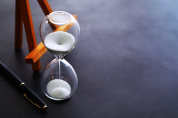 Sand running through the bulbs of an hourglass measuring the passing time in a countdown to a...