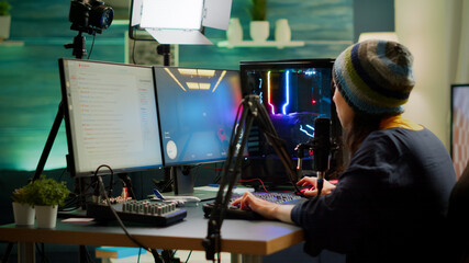 Professional woman streamer playing FPS games talking into microphone via streaming chat during online esports tournament. Gamer making online videogames with new graphics on powerful computer © DC Studio