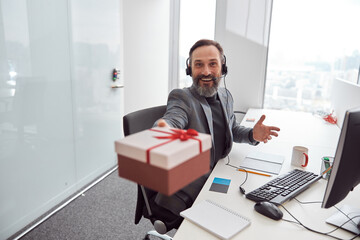 Happy office worker is holding a present and smiling