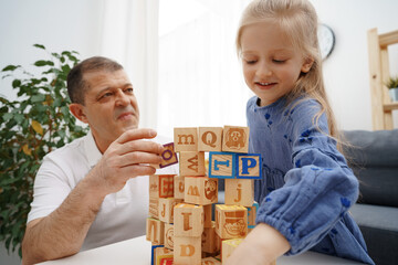 Grandfather and granddaughter playing wooden cubes in living room