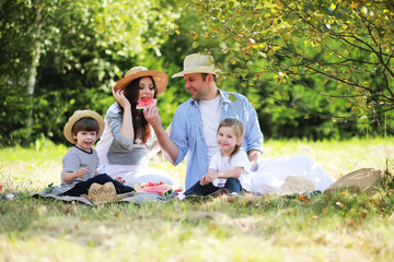 Happy family with children having picnic in park, parents with kids sitting on garden grass and...