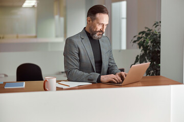 Fototapeta premium Happy adult caucasian man is working in a modern office