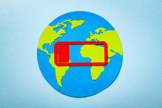 Paper cut concept of planet Earth on the blue background with the charging sign above. Red symbol of almost drained energy.