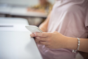 Teenage student typing on cell phone in the classroom.