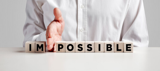 Businessman hand changes the word impossible into possible