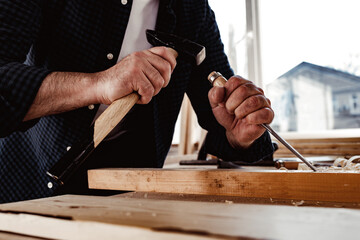 Hands of a carpenter working with chisel and hammer