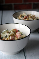 Chickpeas, tomatoes, cucumbers. Salad in a white bowl.