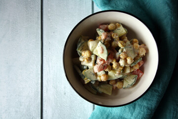 Chickpeas, tomatoes, cucumbers. Salad in a white bowl.