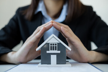 The house is covered by the hands of a real estate agent to protect the house for customers, homebuyers, insurance, ready give to with new owner. Home insurance sales concept
