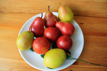 Three red oranges and pears of yellow and red color.