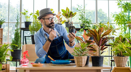 An elderly man handsome with have mustache wearing glasses is happy with tree care. is a hobby of gardening at home, living happily after retirement. Concepts nature and environment