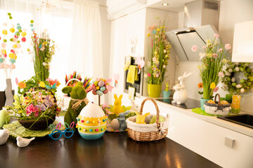 Easter decorations in the house. Easter bunny, easter eggs in basket and cabbage leaf. Bouquets of spring flowers. 