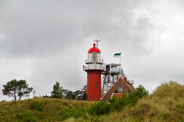 Fototapeta na wymiar The red lighthouse and next to it the lighthouse keeper's house in het dunes of the Dutch island of Vlieland