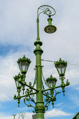 Vintage rusted green lighting pole with cloudy sky in the background on Liberty Bridge (Szabadság híd) over Danube river in Budapest, Hungary .