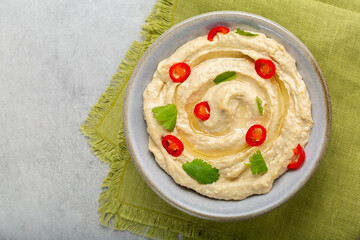 Hummus made from mashed chickpeas, tahini and lemon with olive oil, decorated with hot peper and...